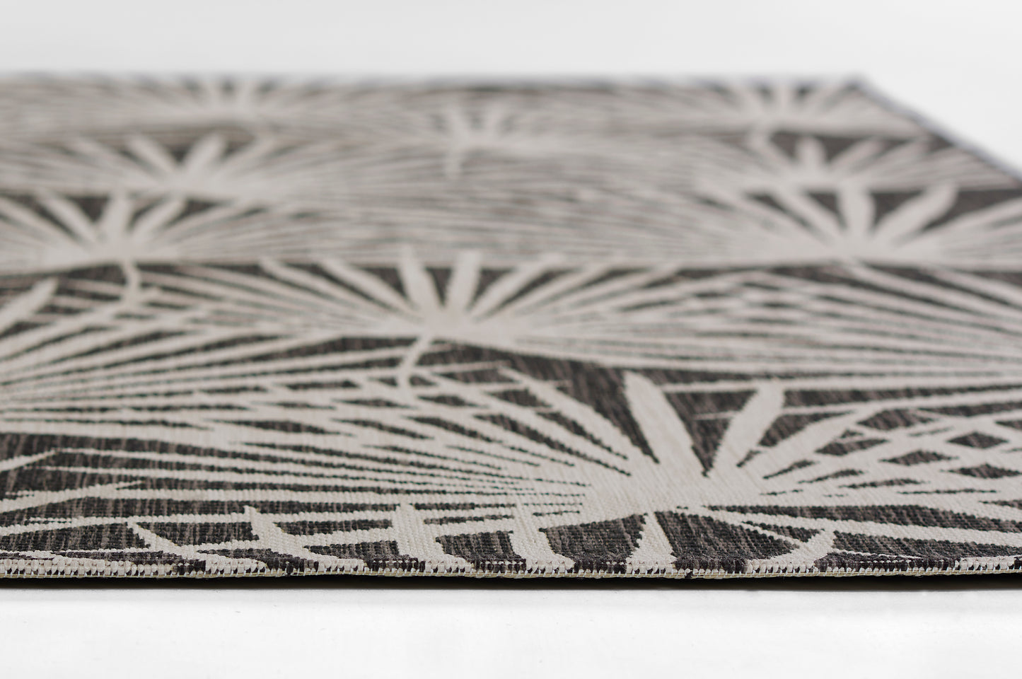 Close-up of black and white palm-leaf patterned rug; woven flatweave textile for modern floor decor.