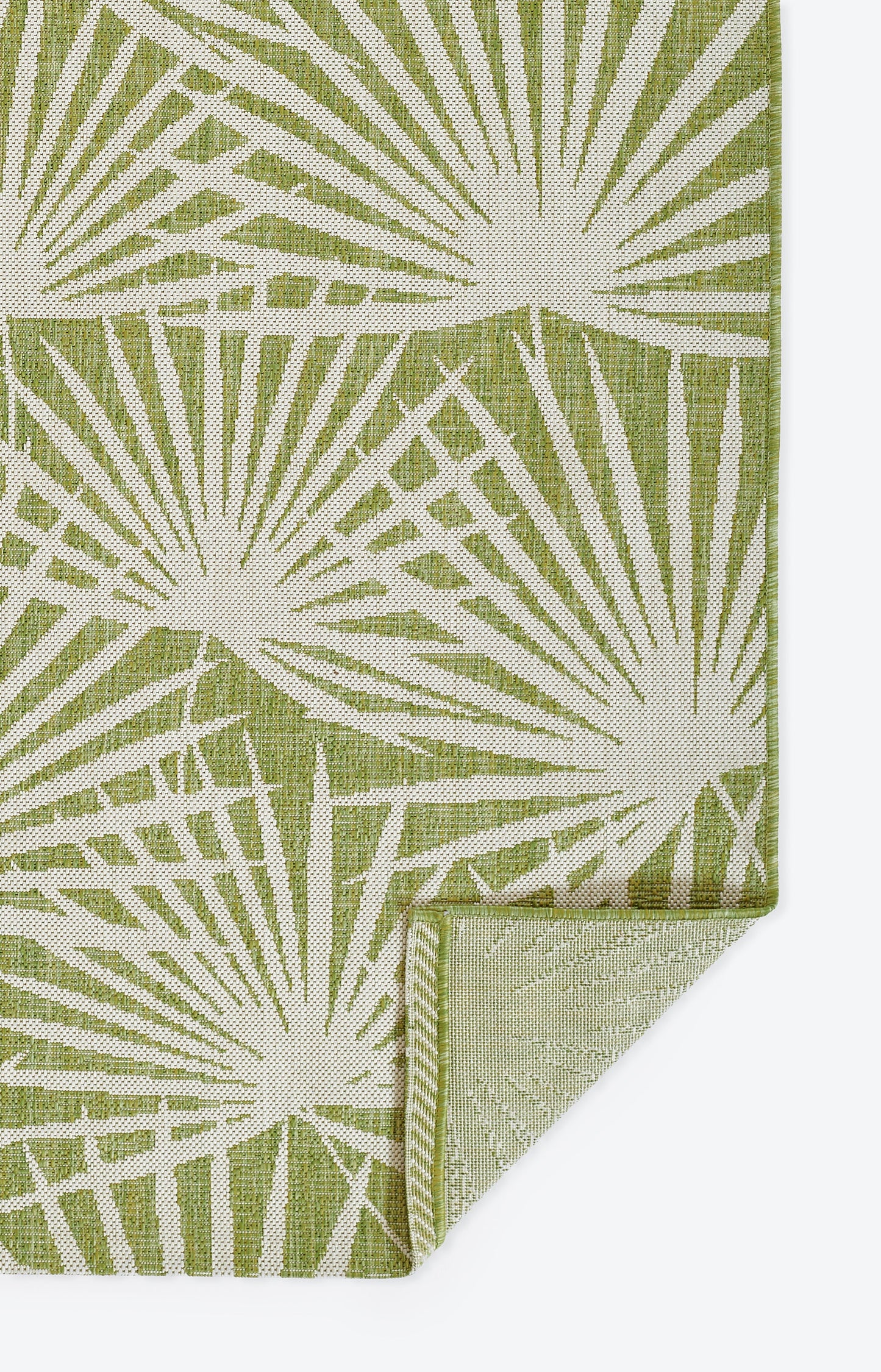 Green rug with a white sunburst motif; folded corner.