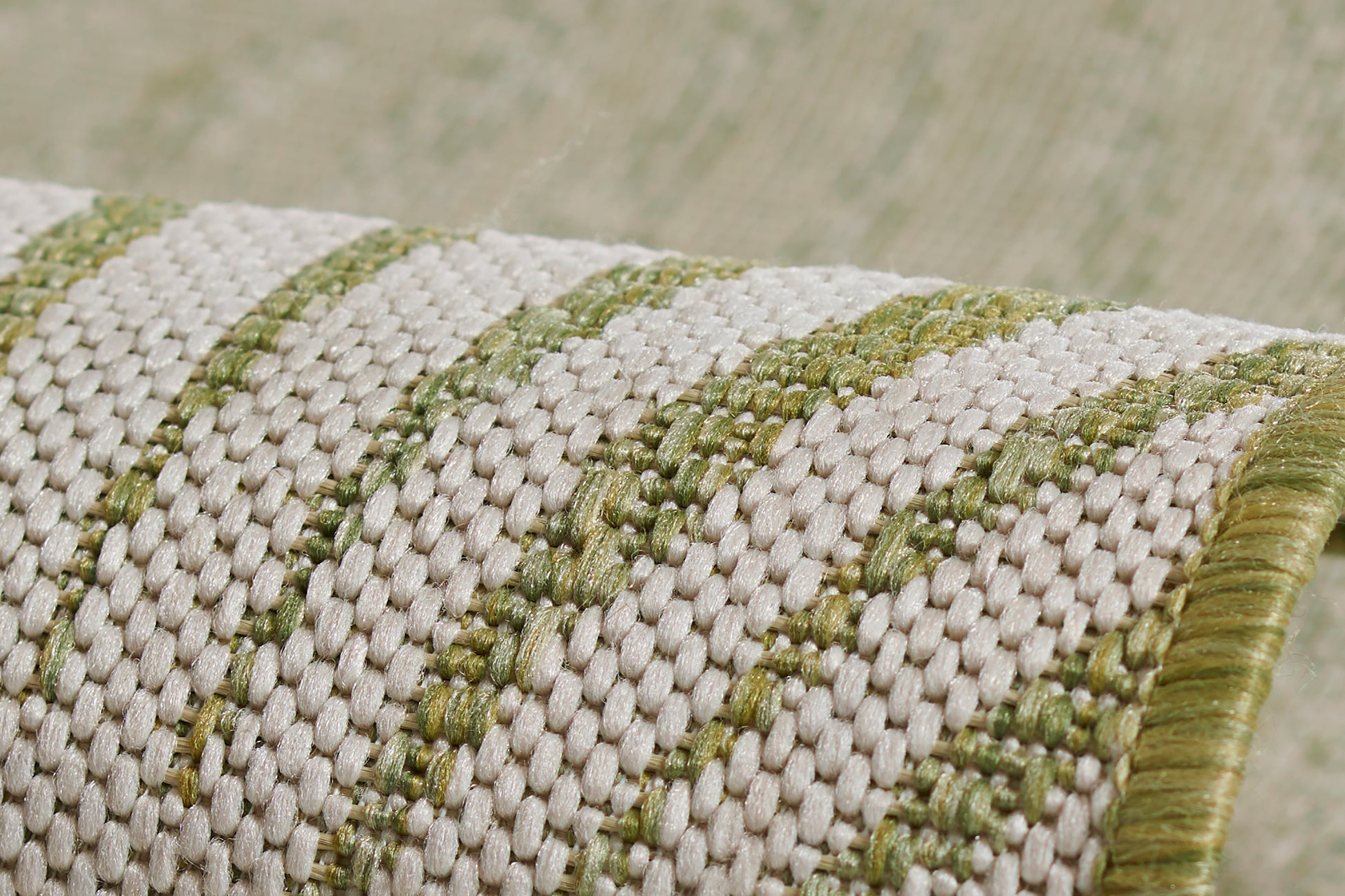 Cream and olive green striped woven rug with a thick textured weave and a green border.