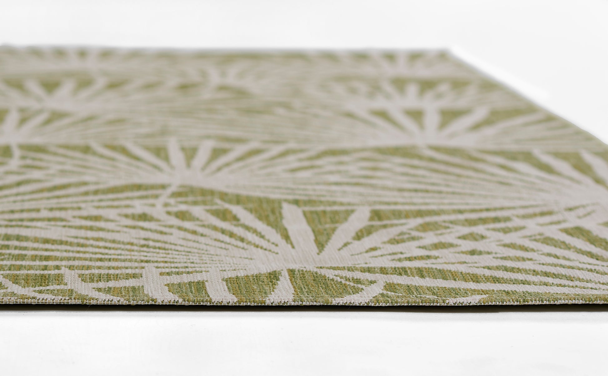 Olive green woven rug runner with white geometric starburst pattern, close-up edge view.