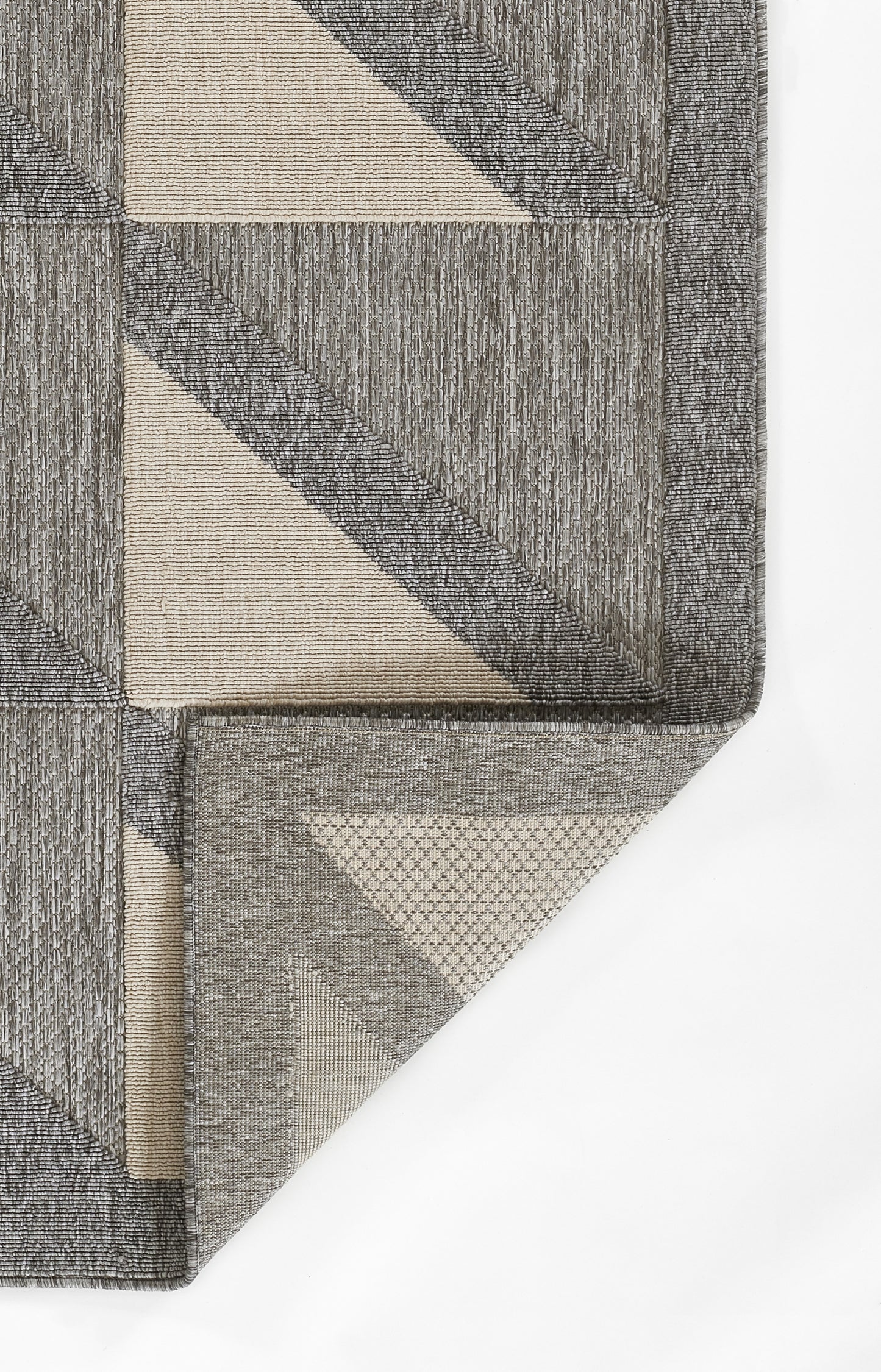 Close-up of a gray rug with a beige vine pattern, textured woven surface, edge fold visible.
