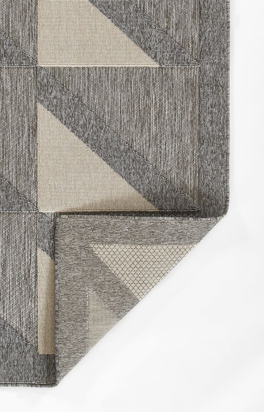 Close-up of a gray rug with a beige vine pattern, textured woven surface, edge fold visible.