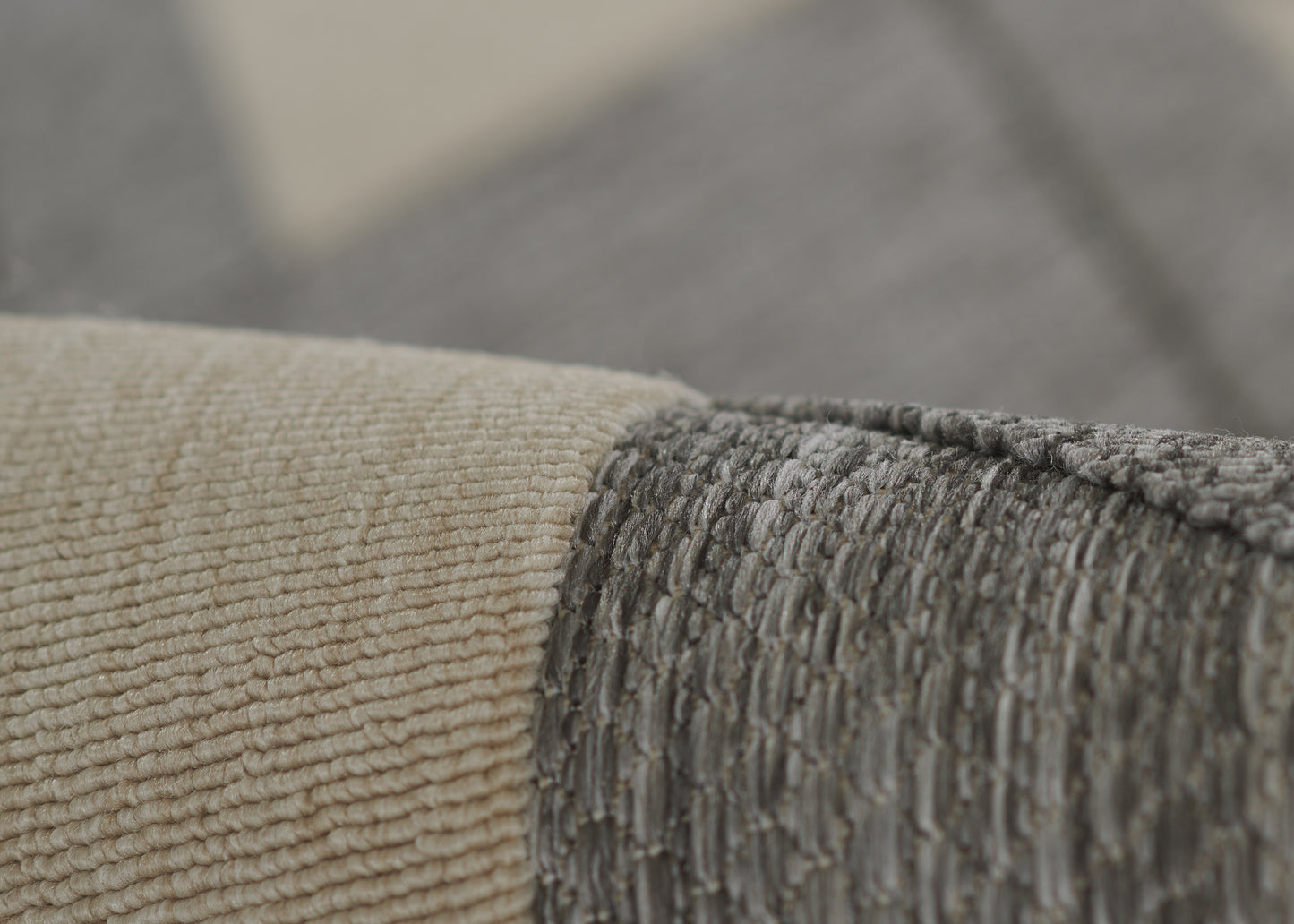 Close-up of beige and gray woven rug with textured loop pile and overlapping seam.