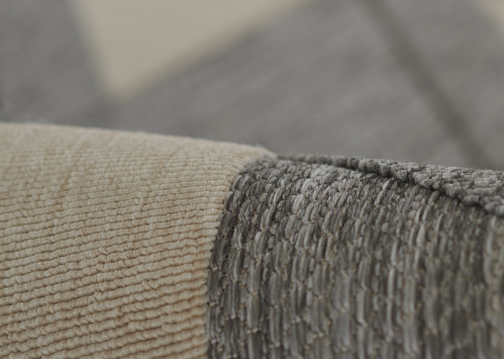 Close-up of beige and gray woven rug with textured loop pile and overlapping seam.