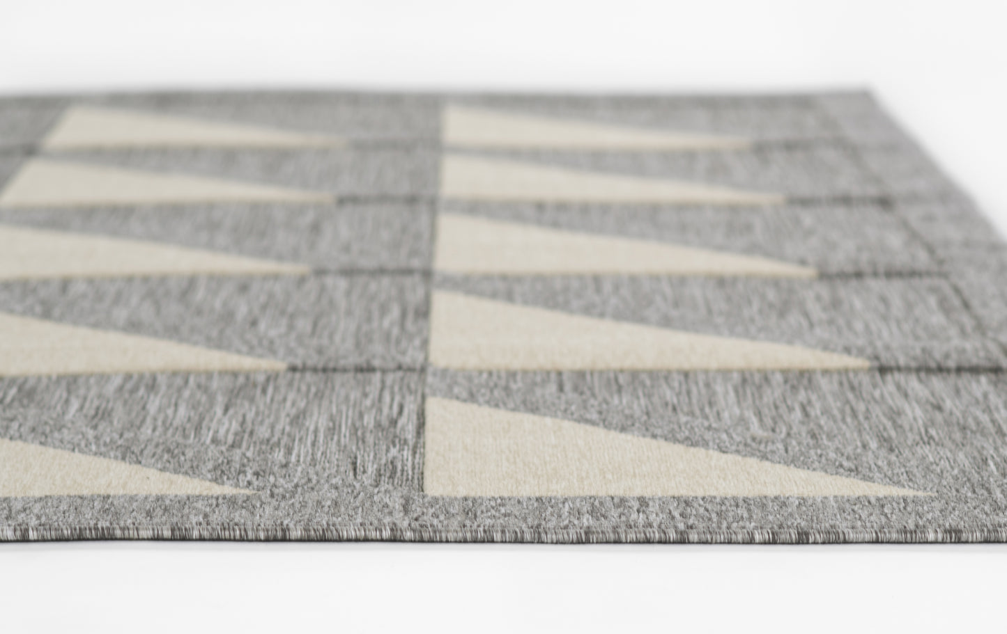 Gray textured woven rug with beige triangular motifs forming a diagonal chevron pattern.