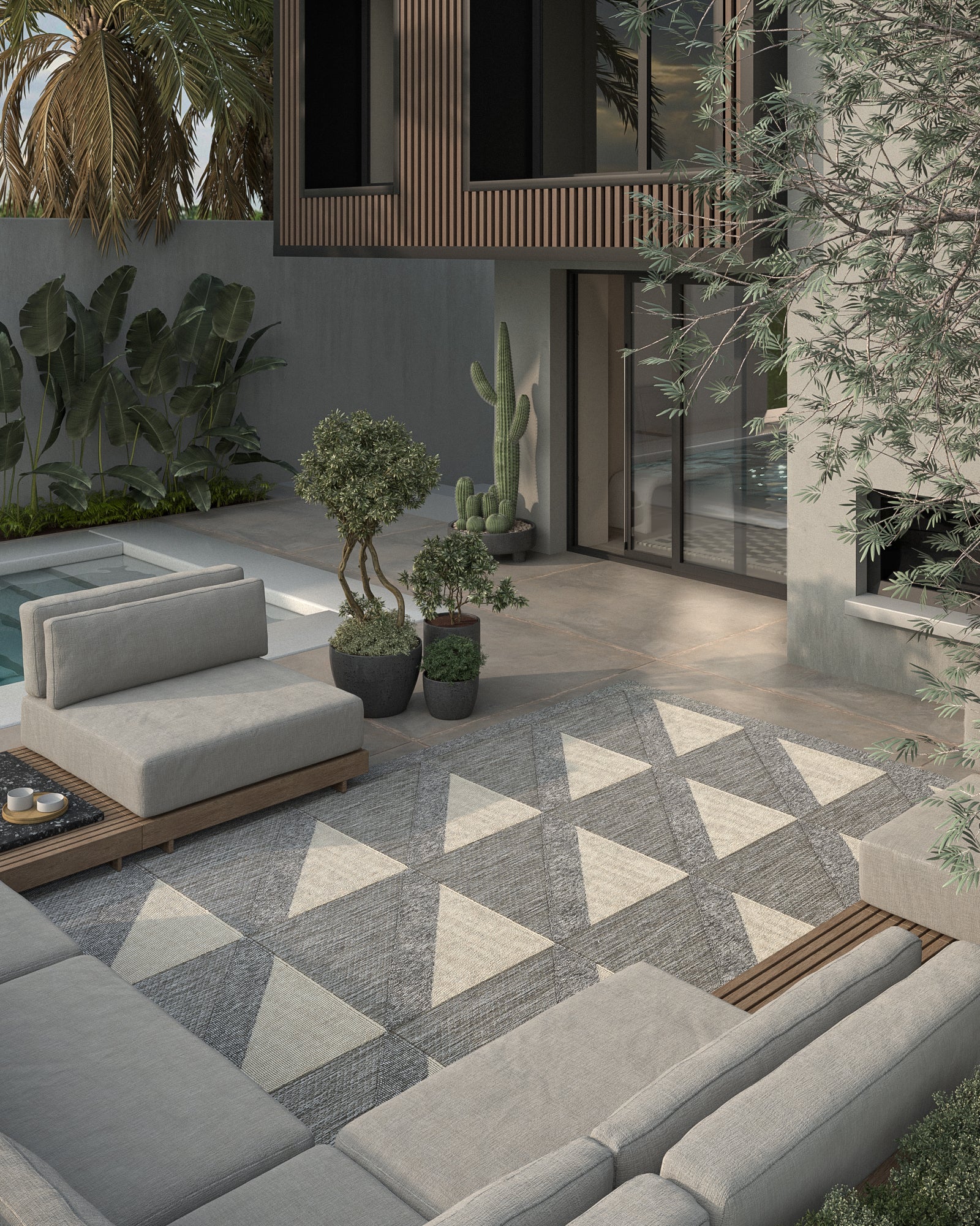 Modern outdoor patio with gray sectional seating, geometric gray-and-white triangle rug, potted plants, and wood accents.