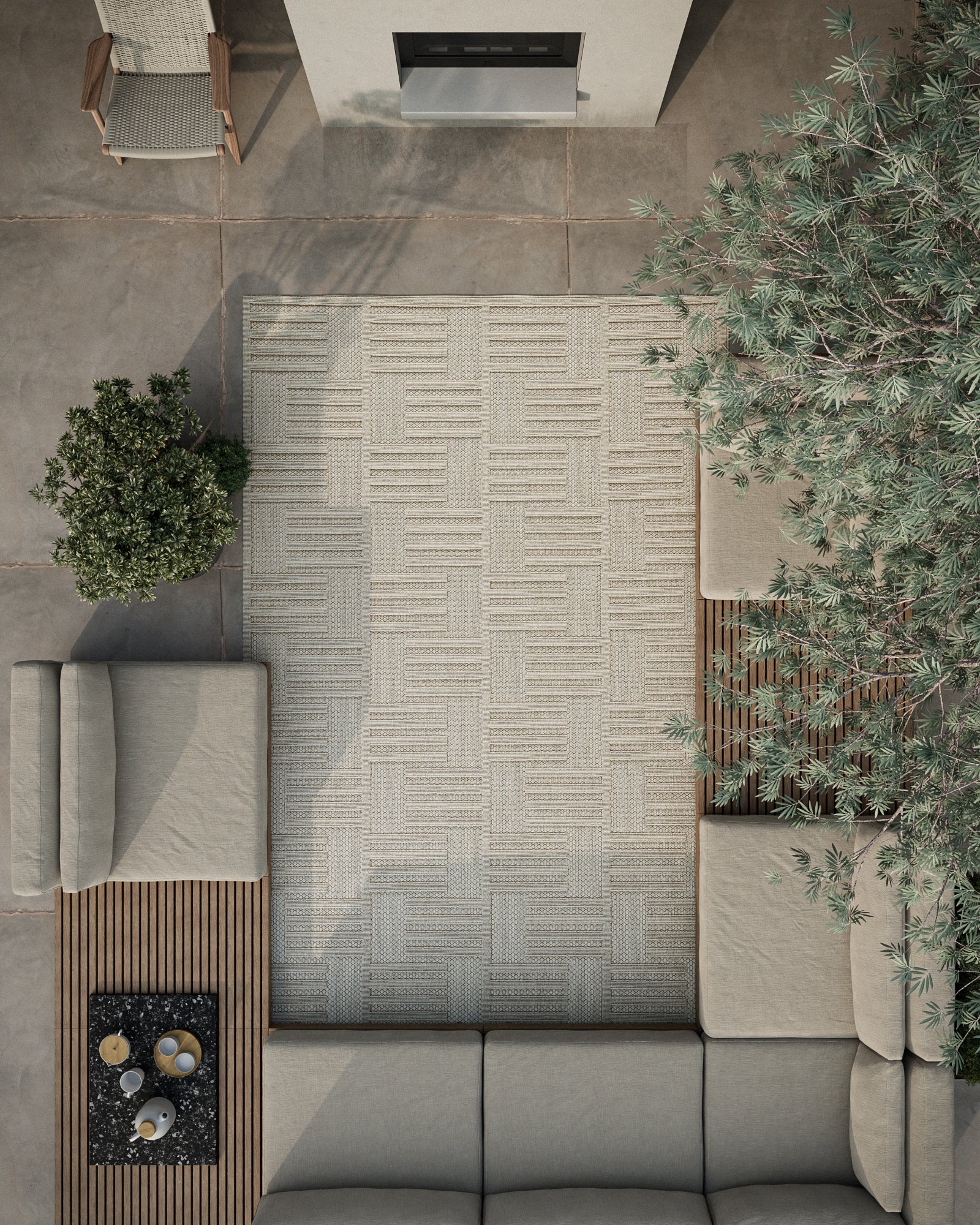 Overhead view of a neutral outdoor lounge with a light gray geometric rug, beige modular sectional & greenery.