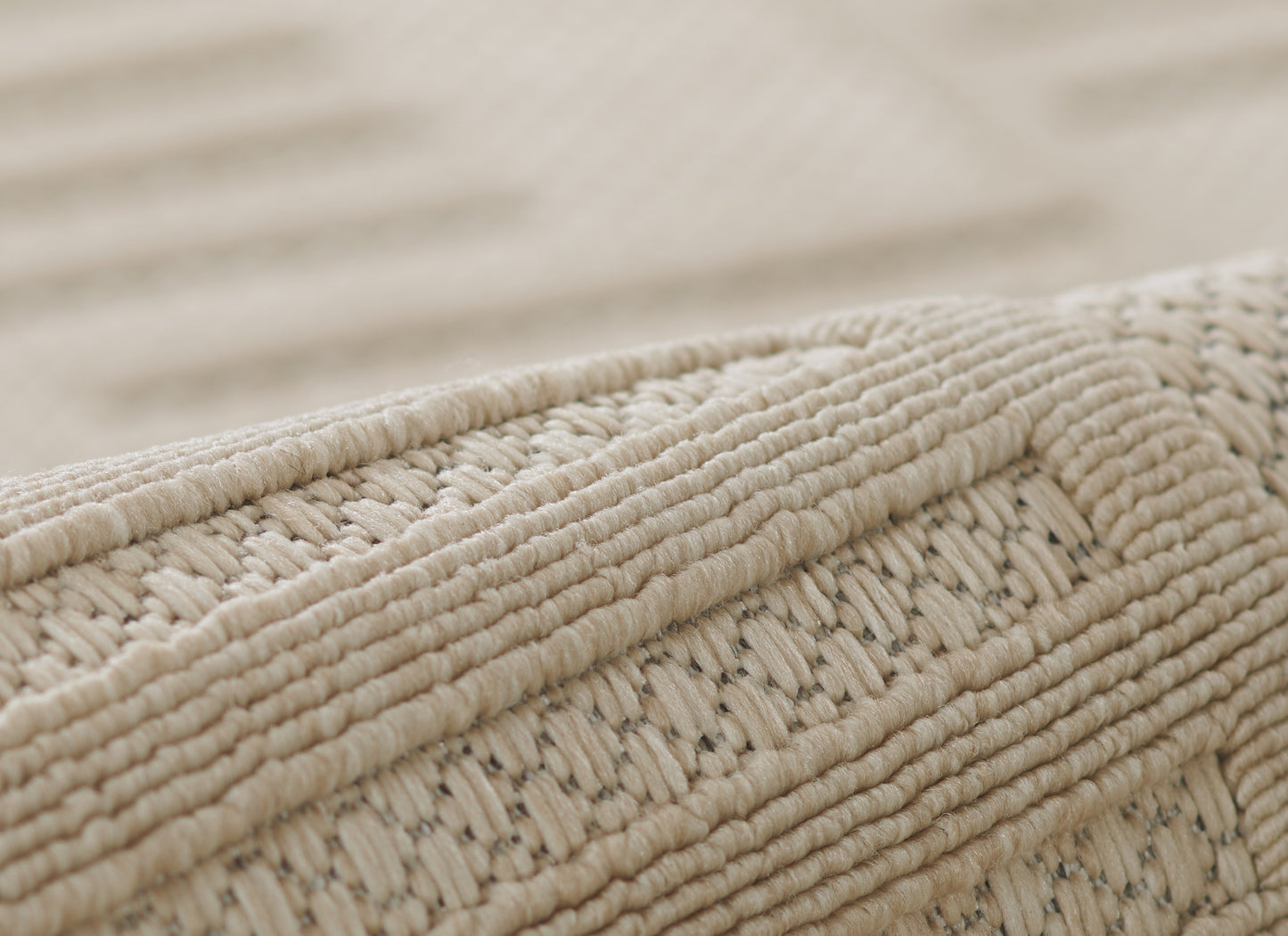 Beige natural-fiber braided rug close-up showing thick woven texture and edge.