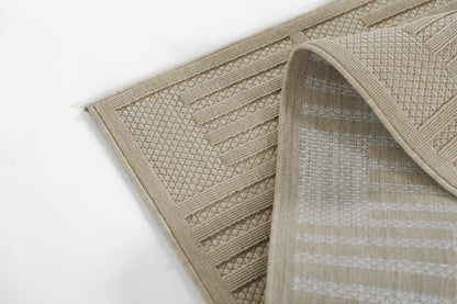 Beige woven area rug with striped and geometric patterns, folded to show fringe edge; neutral home floor decor.