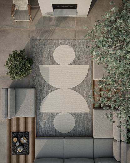 Modern gray outdoor seating on a geometric rug with circle shapes, potted plants, and fireplace wall.