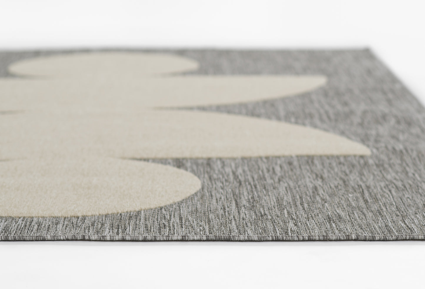 Close-up of gray textured runner with oversized beige leaf shapes; modern, woven floor mat.