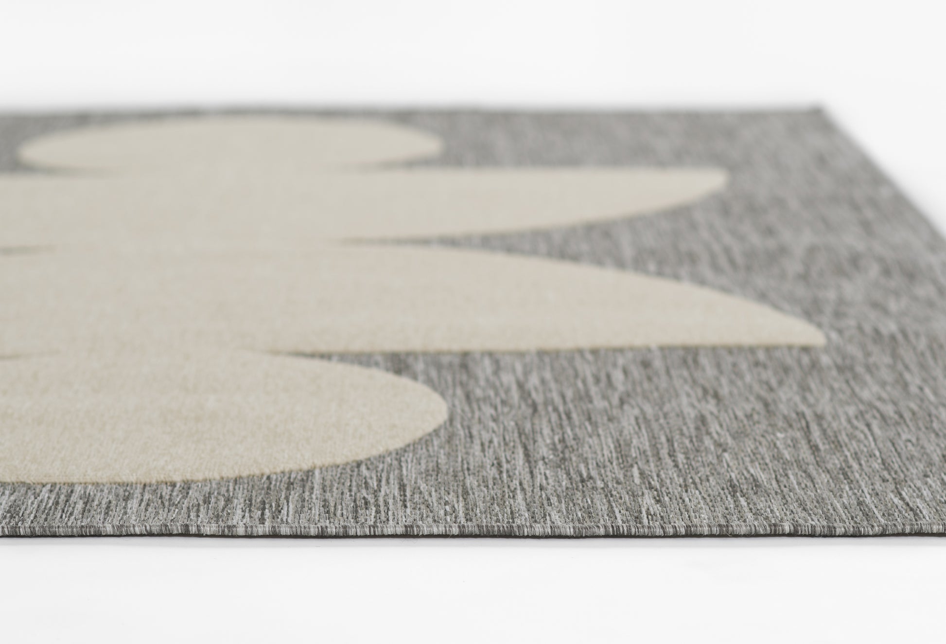 Close-up of gray textured runner with oversized beige leaf shapes; modern, woven floor mat.