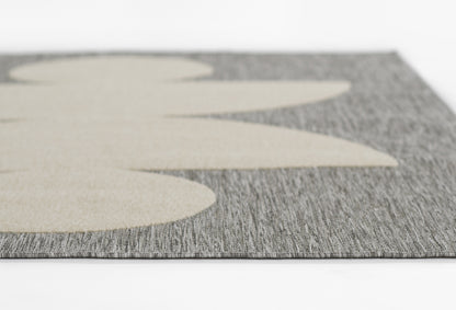Close-up of gray textured runner with oversized beige leaf shapes; modern, woven floor mat.