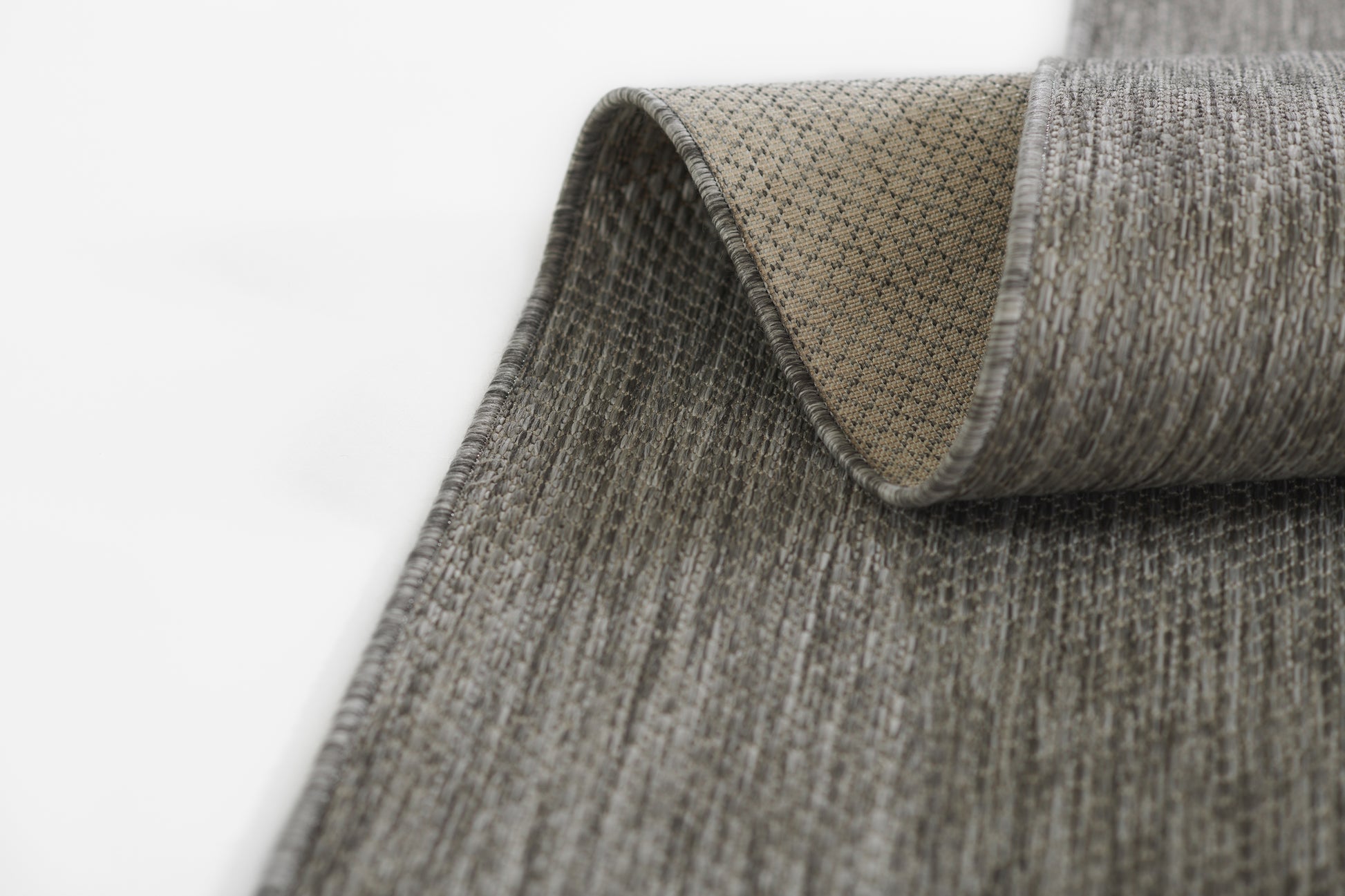 Grey textured ribbed rug runner with beige backing, partially rolled to show the underside.