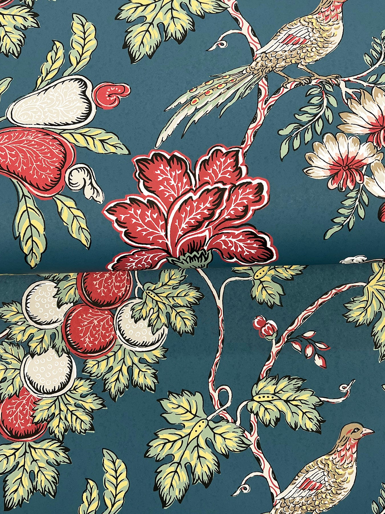 Indigo Jacobean wallpaper with a vintage botanical pattern featuring red-fruited vines, pale-yellow leaves, and perched birds.
