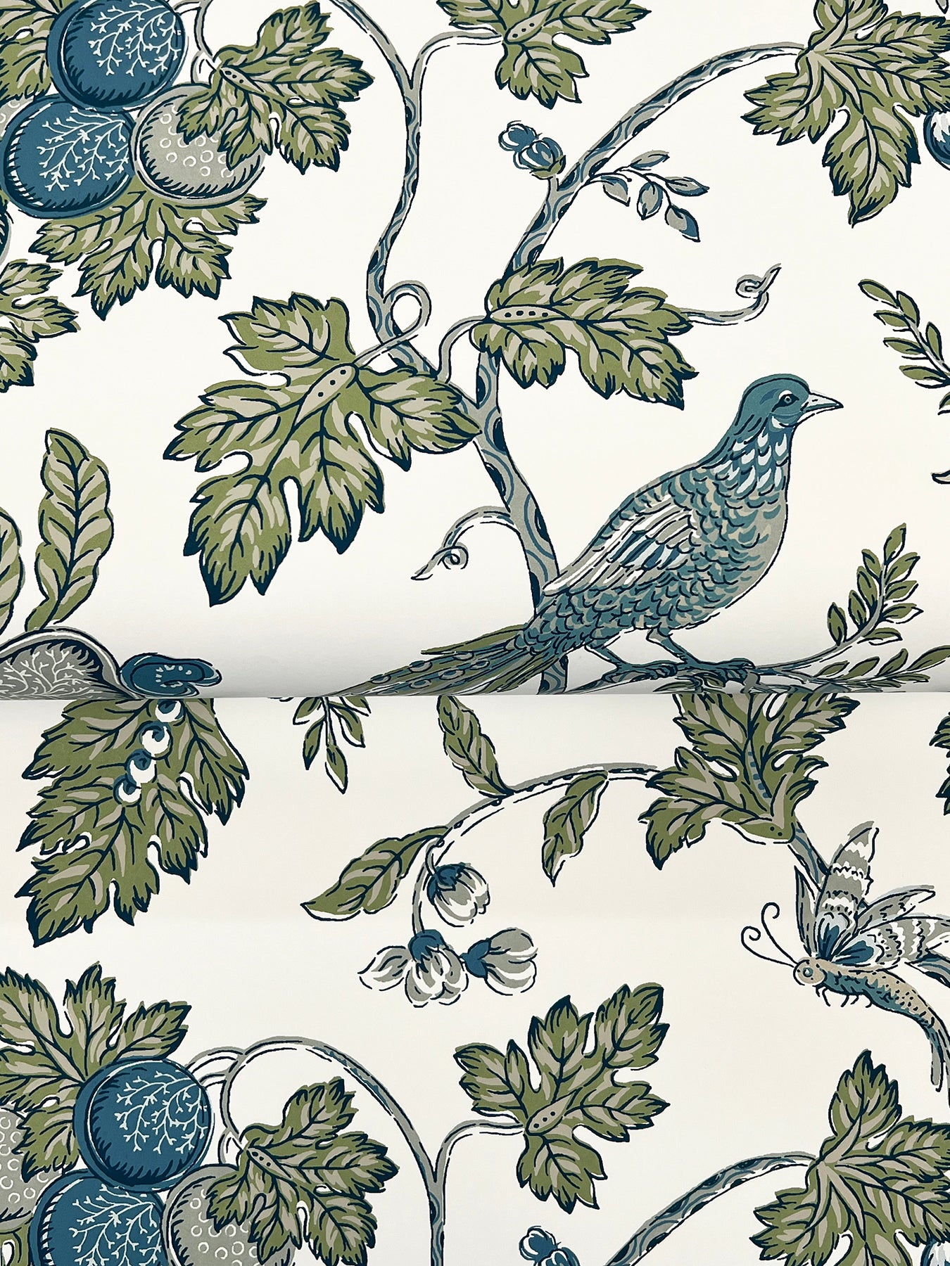 Floral toile pattern with blue-green birds perched on leafy vines and blue fruit on ivory background.