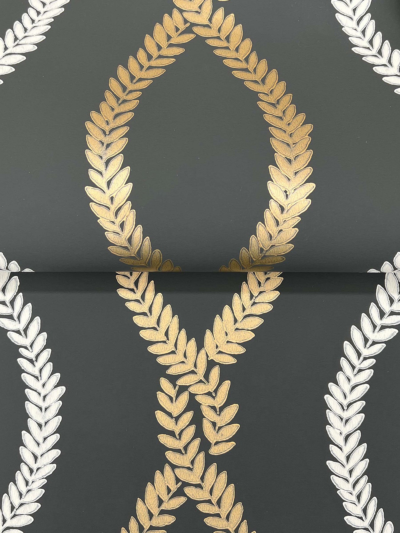 Dark gray fabric with metallic gold laurel leaf teardrop motif and white laurel borders; damask-style print.