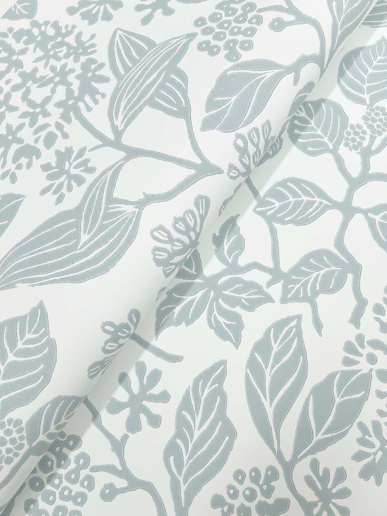 Close-up of pale blue-gray botanical print on ivory fabric; leaves and clusters of small flowers.