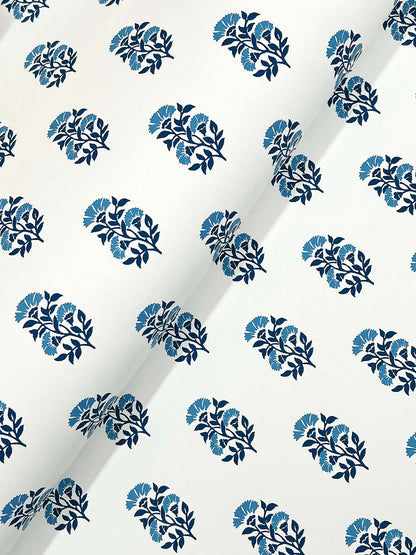 White fabric with repeating circular clusters of blue leaves in navy and light blue; diagonal crease across the print.