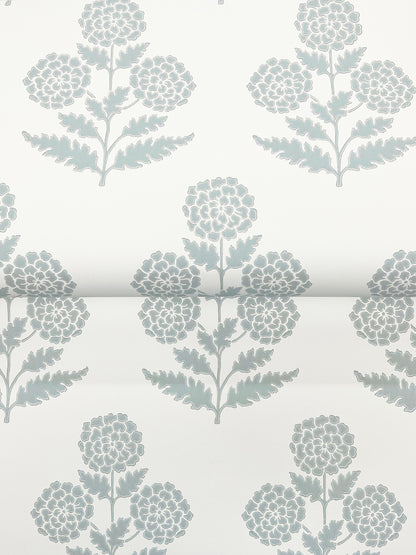 Pale blue wallpaper with marigold blossoms and botanical leaves in a modern botanical design.