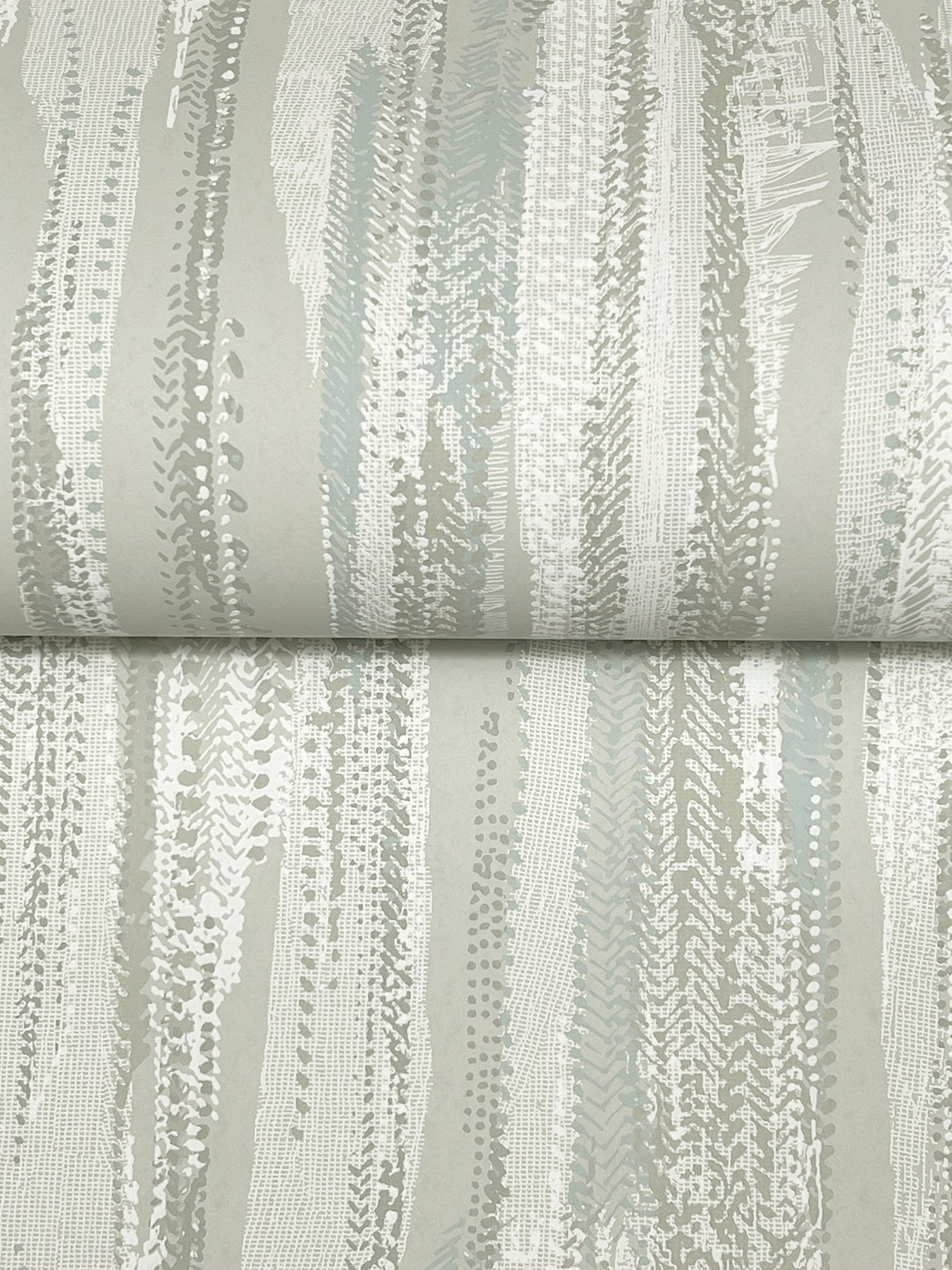 Roll of fabric with abstract vertical brush-stroke pattern in gray, taupe and pale blue on beige; modern upholstery textile.