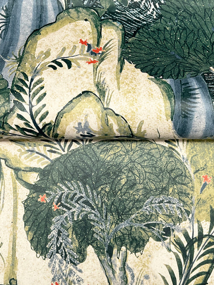 Close-up of rainforest botanical print in greens with beige rock backdrop and small red flowers on fabric.