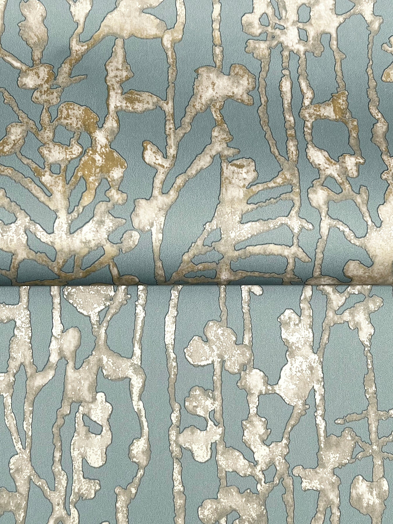 Blue-gray fabric with cream textured coral-like pattern and metallic accents; upholstery or drapery textile.