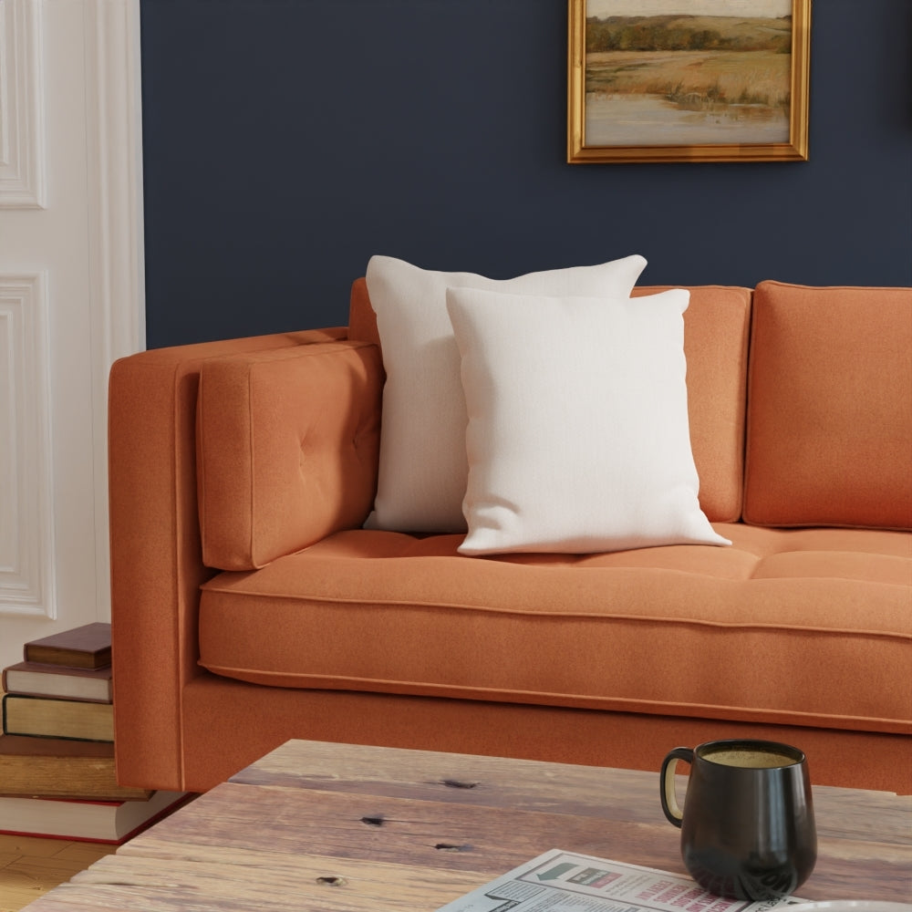 Cream solid fabric upholstery on seating & white cushions in a navy living room; wooden coffee table with a black mug.