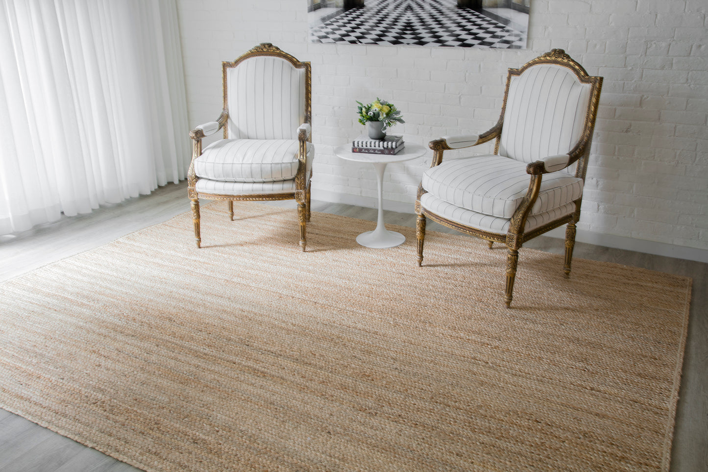 Beige jute runner rug on the floor with two white & gold carved chairs & a white round side table nearby.