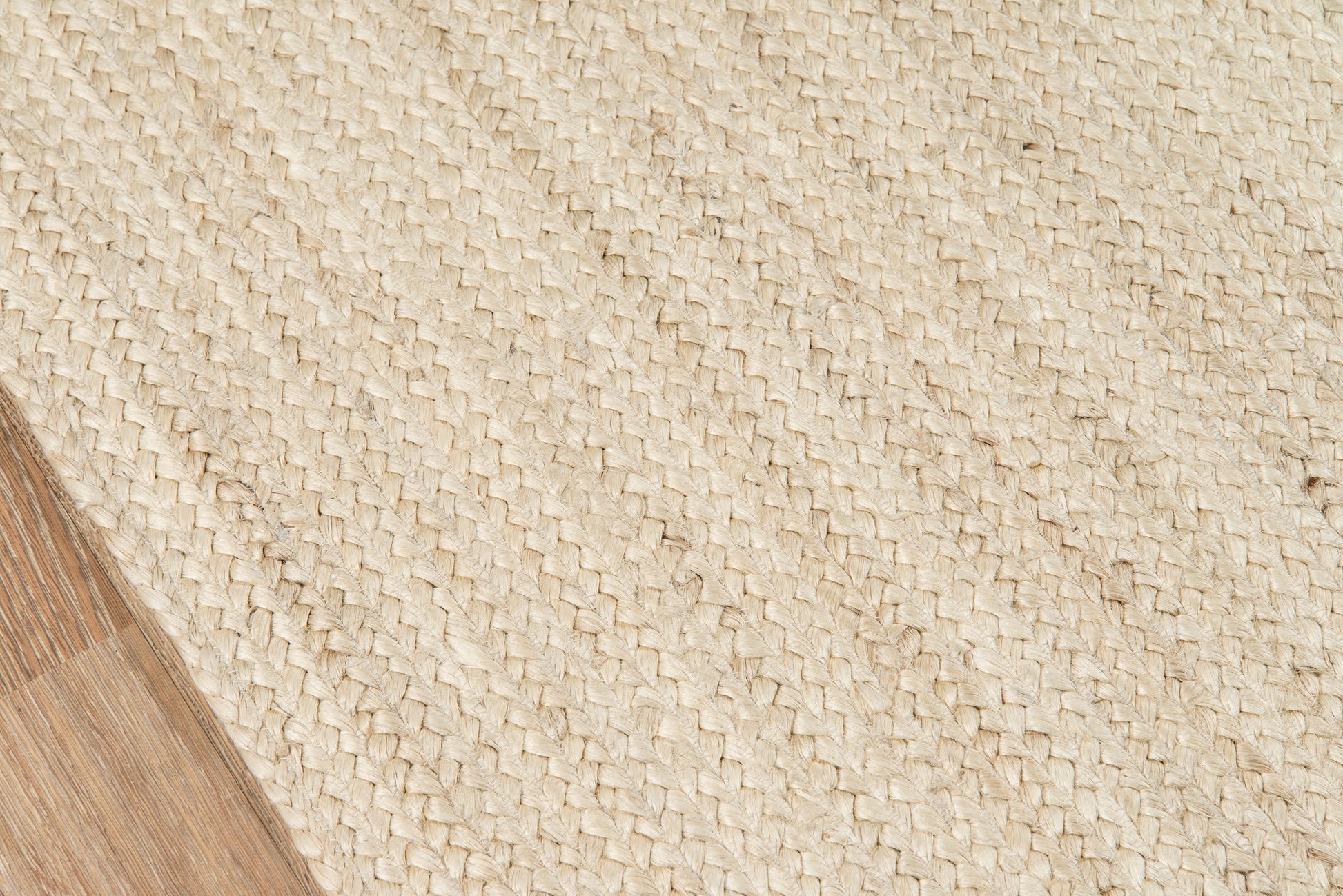 Natural beige woven jute runner; textured diagonal weave, corner on wooden floor, rustic & coastal style.