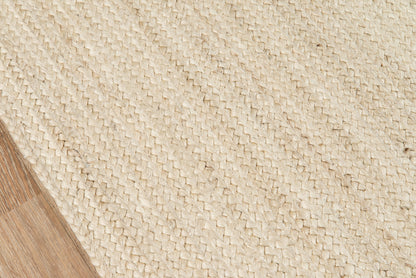 Natural beige woven jute runner; textured diagonal weave, corner on wooden floor, rustic & coastal style.