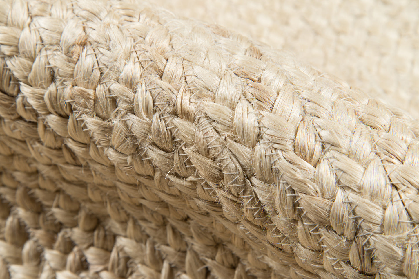 Close-up of natural beige straw weaving with thick braided fibers on a rug runner.