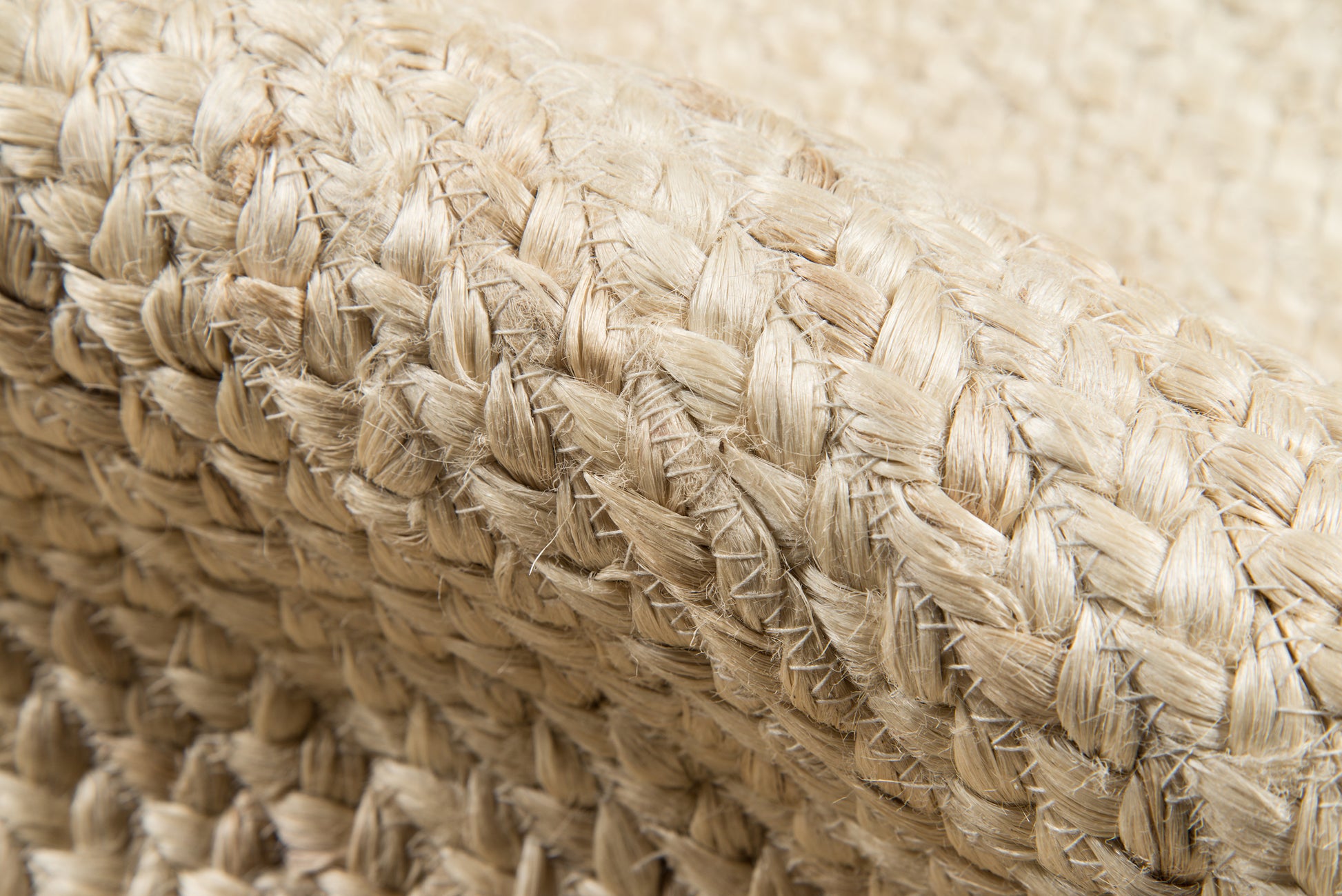 Close-up of natural beige straw weaving with thick braided fibers on a rug runner.