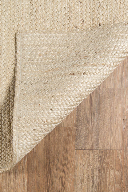 Natural beige jute rug with textured woven surface on wooden floor.