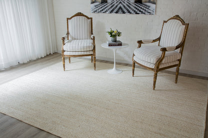 Two ornate carved-wood armchairs with striped beige upholstery beside a white round side table and a plant on a beige runner rug.
