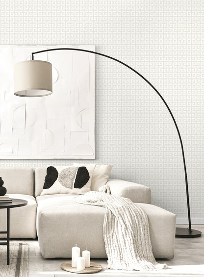 Beige sectional with chunky knit throw under a curved black arc floor lamp, white geometric wall art in modern living room.