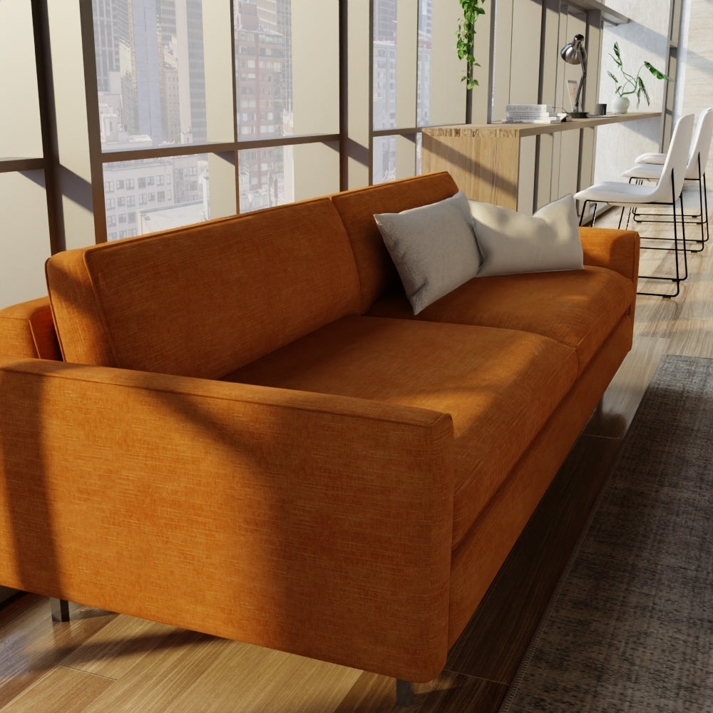 Copper solid fabric upholstery on a sofa with square arms and gray cushions in a bright open-plan loft living area.