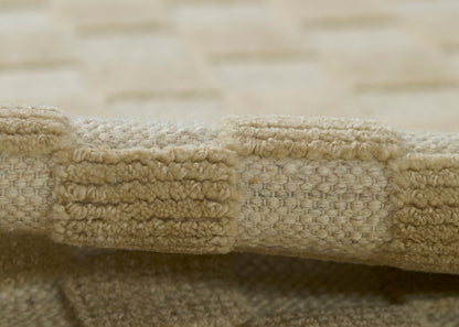 Beige woven rug edge with chunky looped fringe and textured pile.