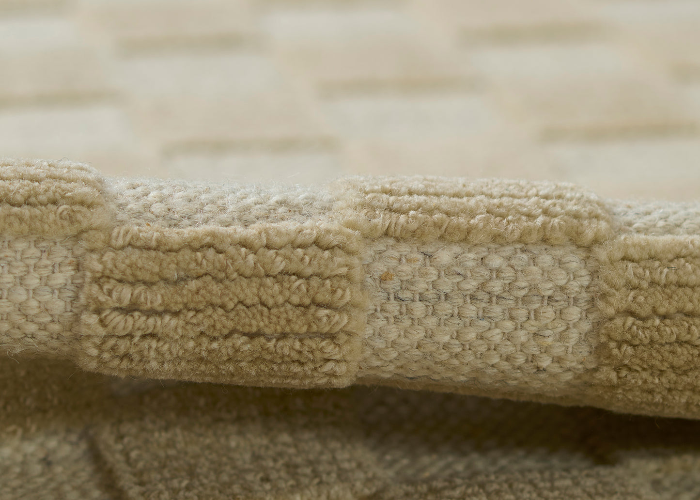 Beige woven rug with tight looped pile and textured neutral tones.