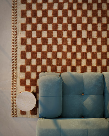 Blue tufted sofa beside a brown-and-beige checker rug with a small round white side table.