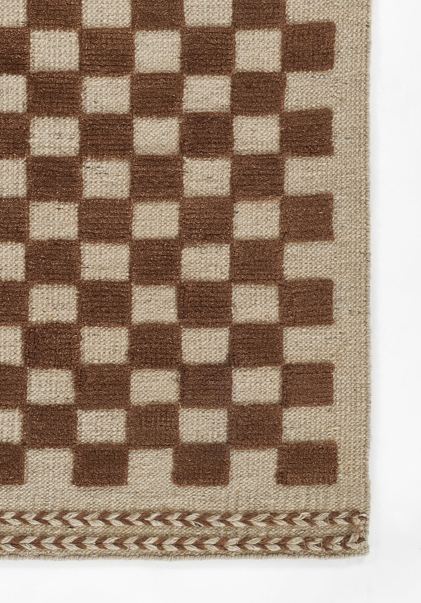 Beige woven rug with a brown checkerboard pattern and a decorative braided edge along the bottom.
