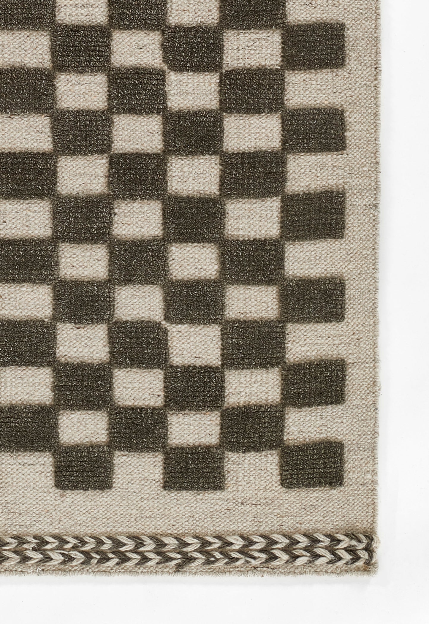 Beige woven rug with dark brown checkerboard squares and a braided border along the bottom.