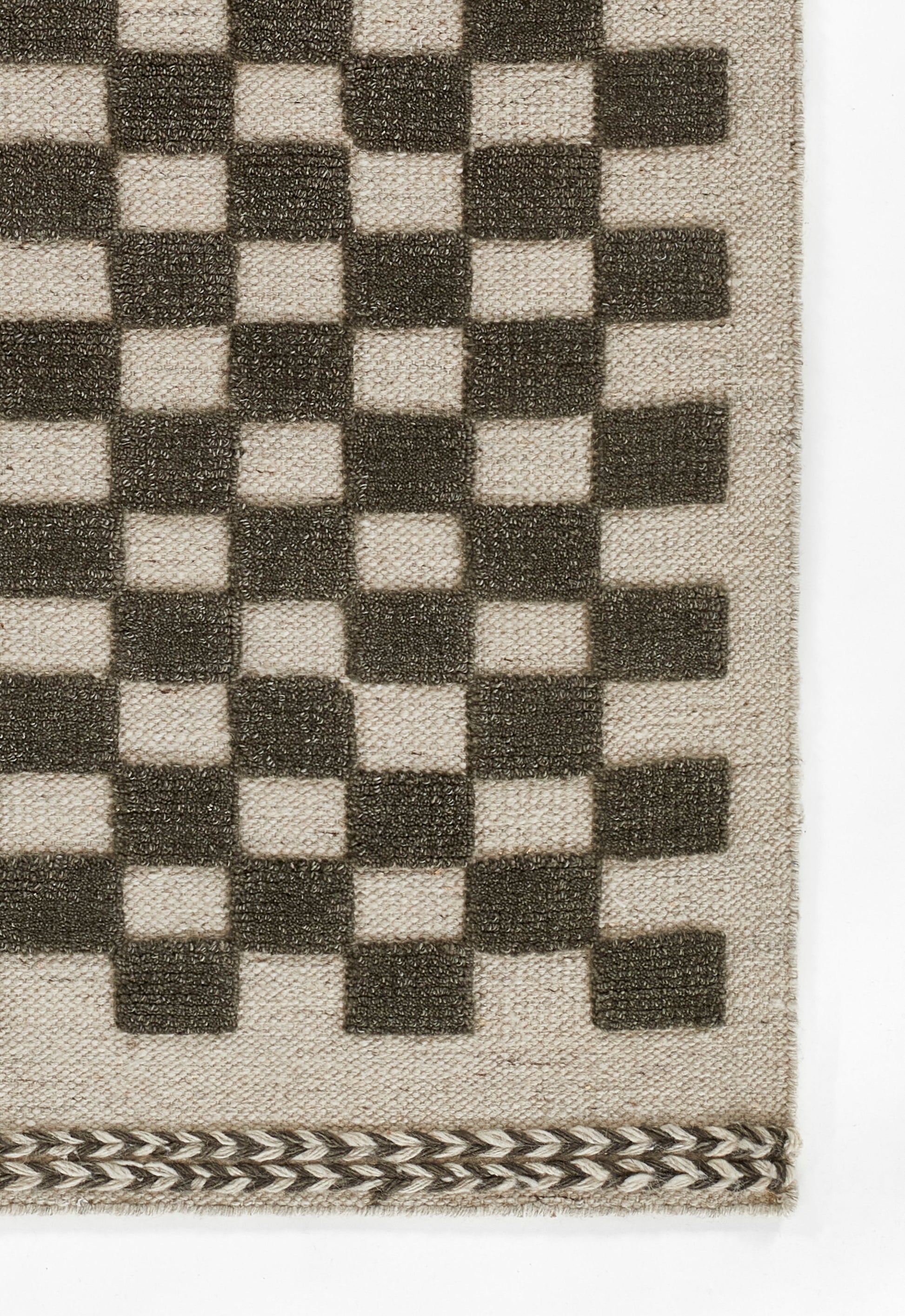 Beige woven rug with dark brown checkerboard squares and decorative chevron border along the bottom edge.