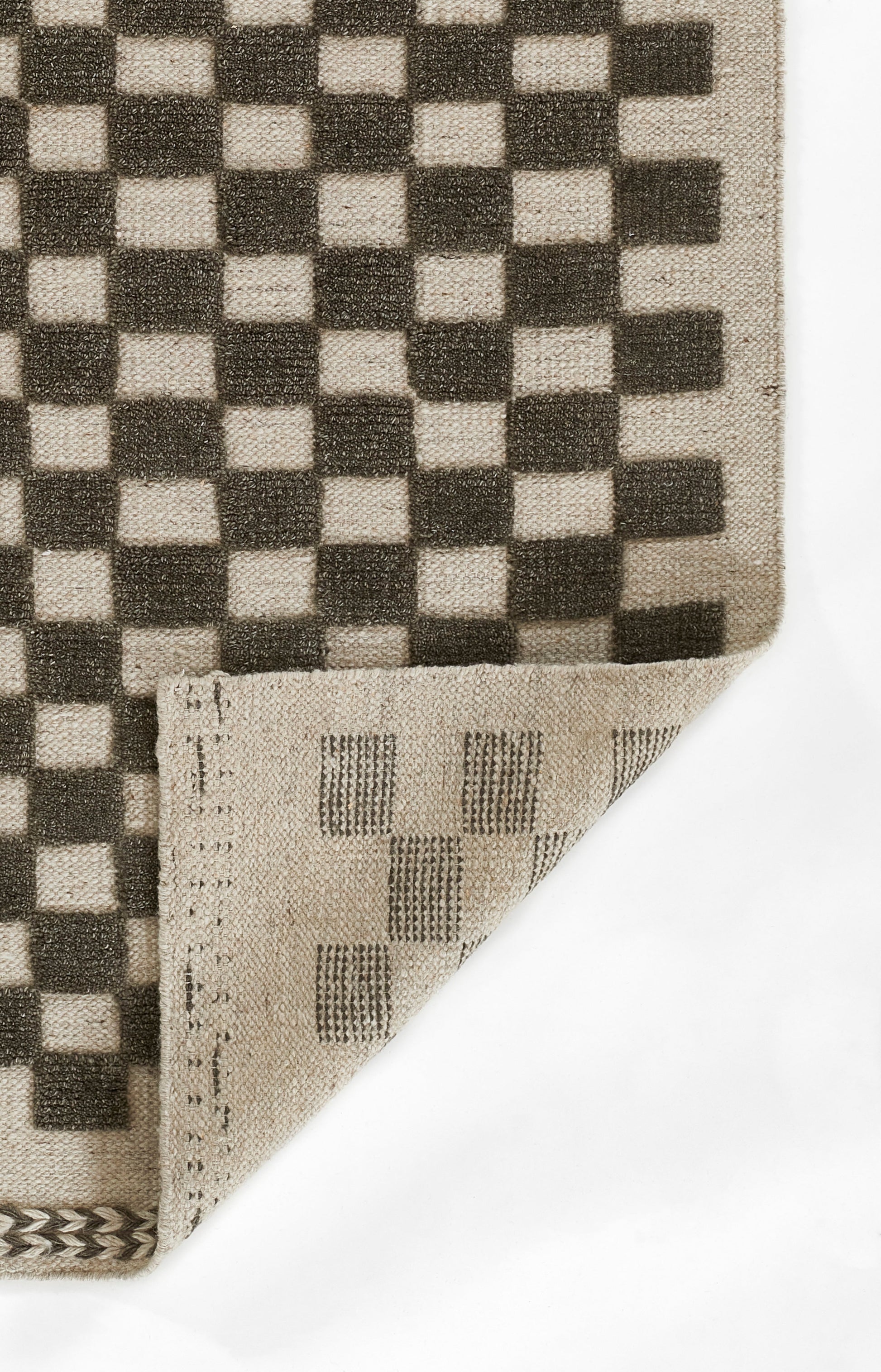 Beige and dark brown checkerboard woven rug, rectangular 9' x 12', folded corner reveals striped reverse.
