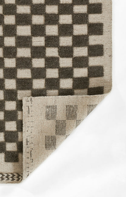 Woven rug with a bold beige and black checkerboard pattern; folded corner reveals the striped reverse.