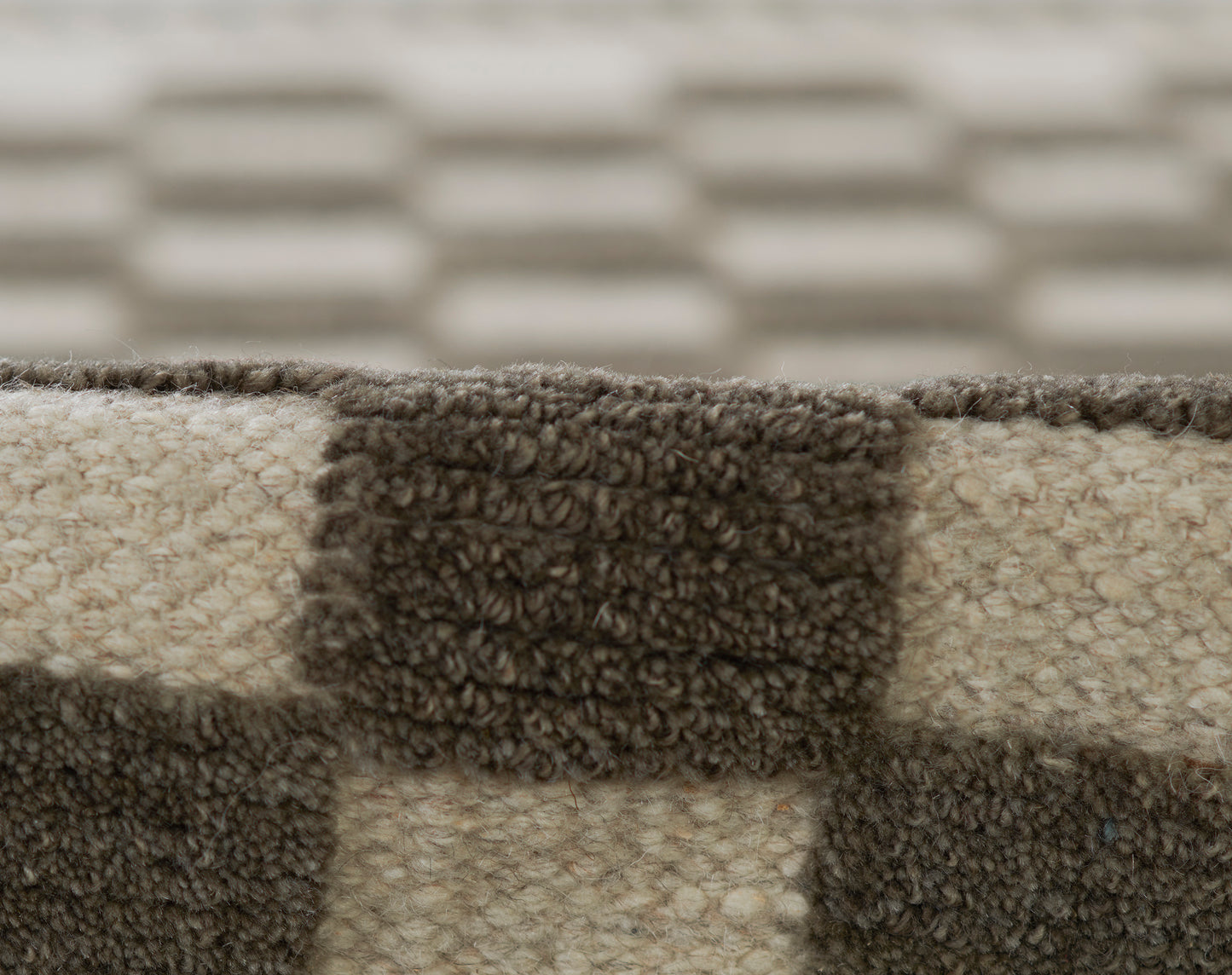 Beige and dark brown checkerboard shag rug with thick tufted pile, close-up.