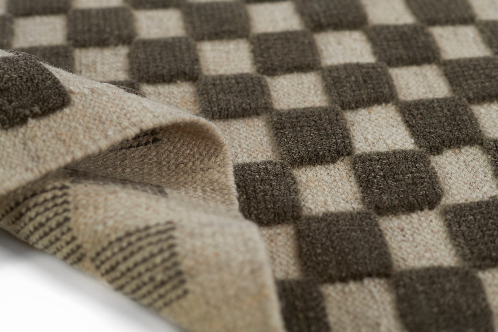 Close-up of brown and beige checkerboard woven rug with a folded edge.
