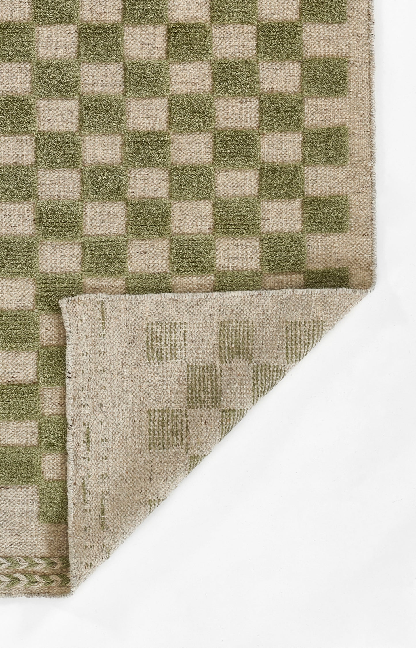 Green and beige woven checkered rug with folded corner, natural fiber texture.