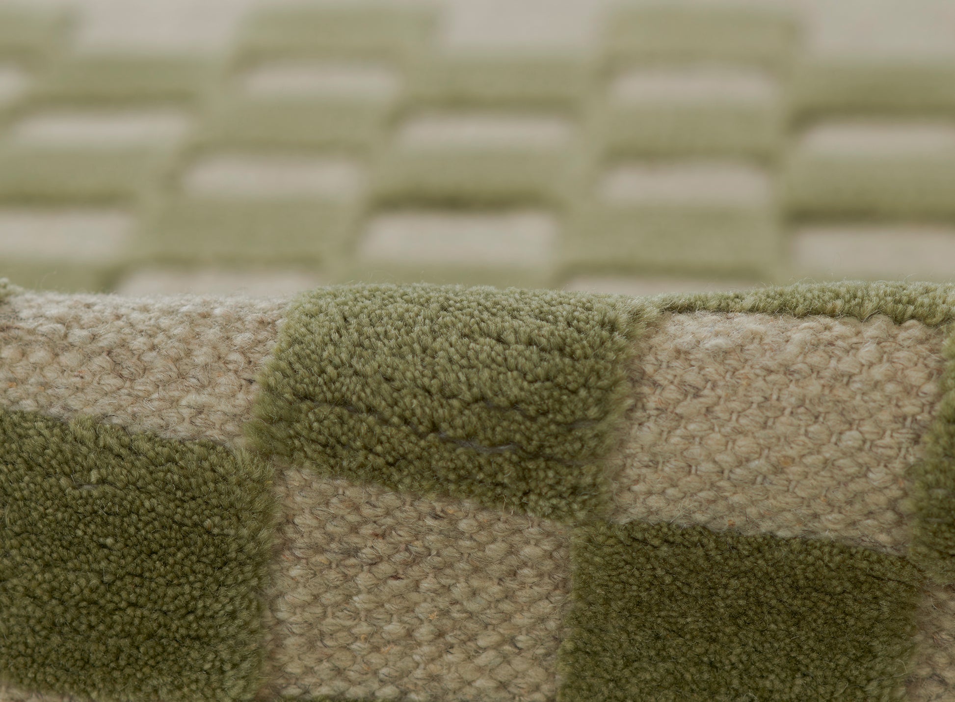 Close-up of olive green and beige checkered boucle fabric blanket, cozy woven throw.