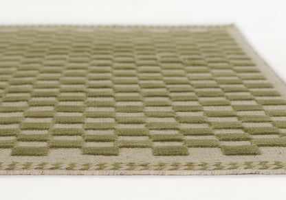 Olive green rug with a raised square-grid pattern and beige braided border, rectangular low-pile woven rug.
